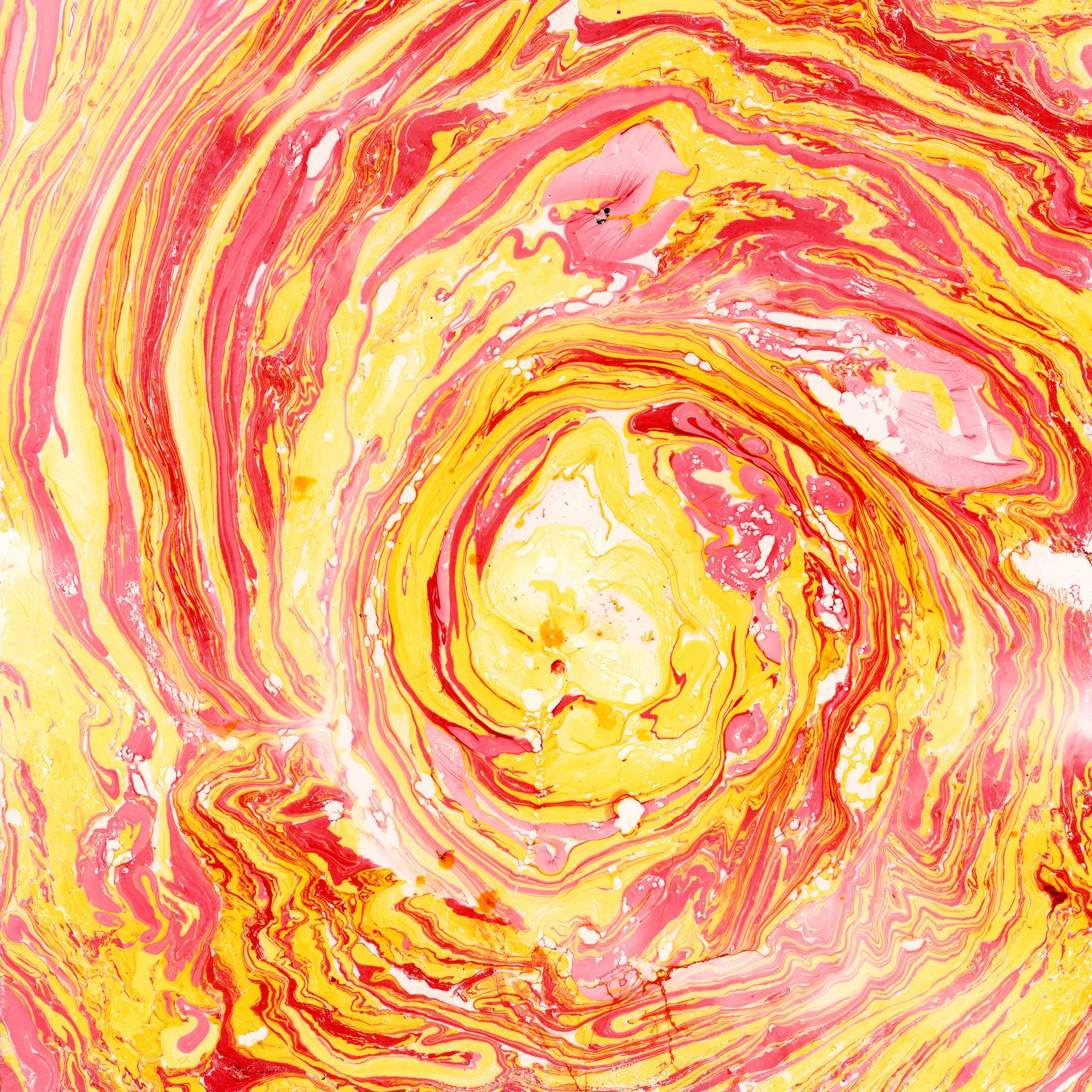 A swirl of marbled red and yellow inks on a square sheet of watercolour paper can be seen. The swirls of colour rotate in a circular fashion towards the centre of the paper, suggesting that we are looking into the eye of a storm.