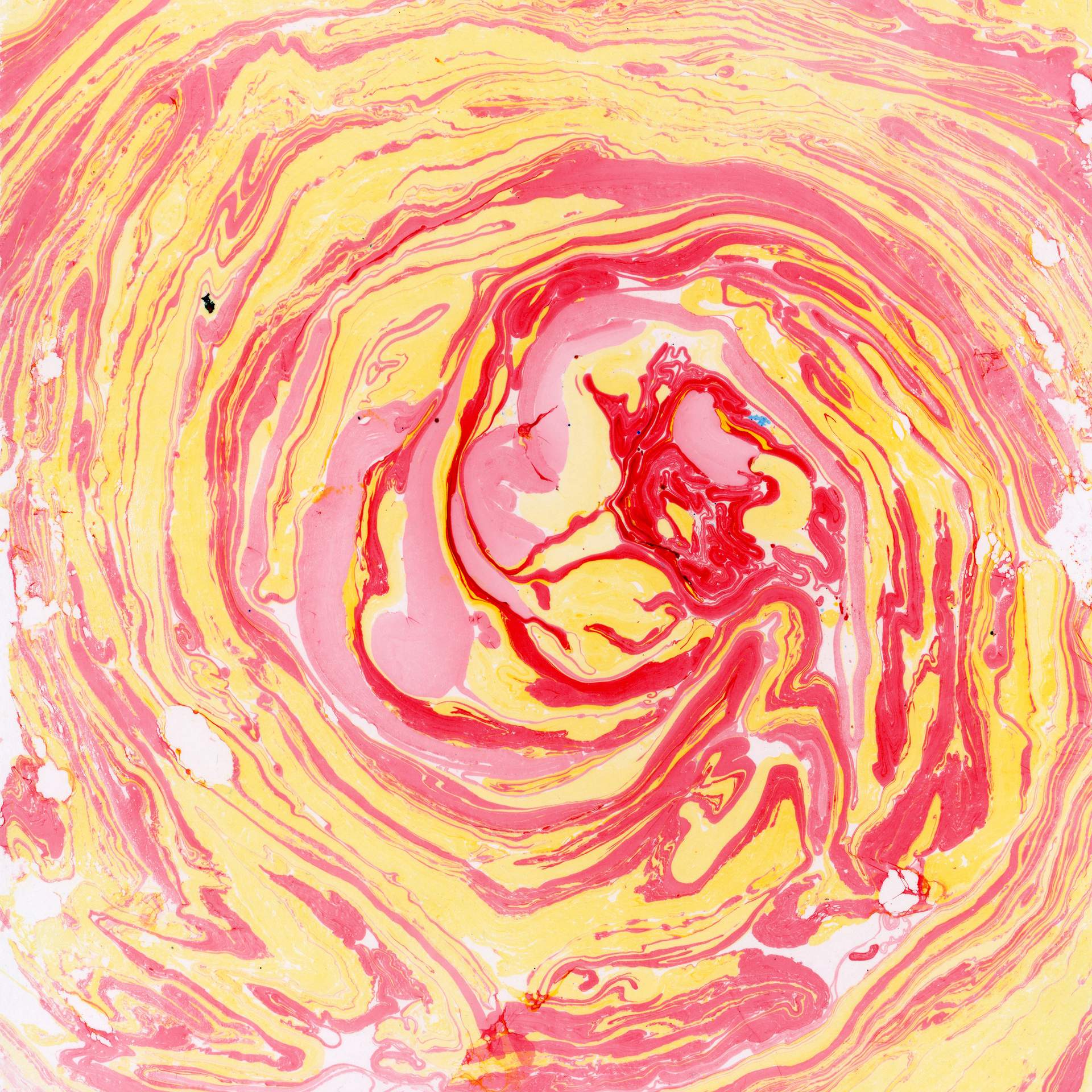 A swirl of marbled red and yellow inks on a square sheet of watercolour paper can be seen. The swirls of colour rotate in a circular fashion towards the centre of the paper, suggesting that we are looking into the eye of a storm.
