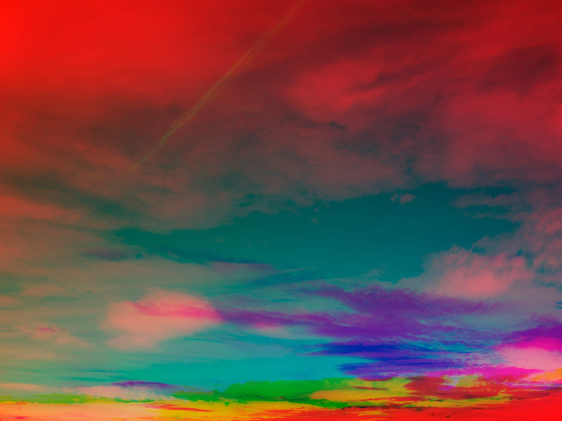 A collage of photographs in an array of hyper-realistic colours. Layers of photographs of clouds can be seen – the nearest clouds are red, while the clouds in the distance are a mixture of purple, green and yellow.